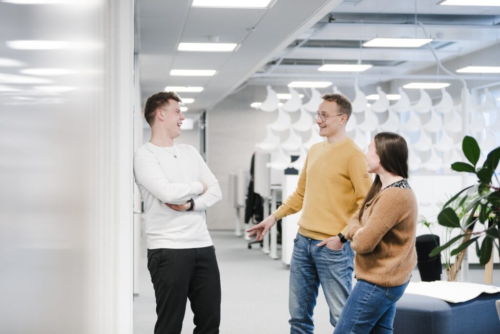 Tiimi keskustelee ja nauraa toimistolla, Alvan henkilöstöä